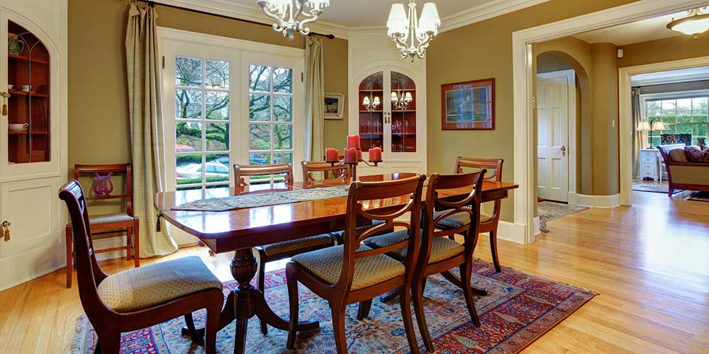 Elegant big dining room with hardwood floor, cherry wooden dining table set, and rustic cabinets seen during a home inspection
